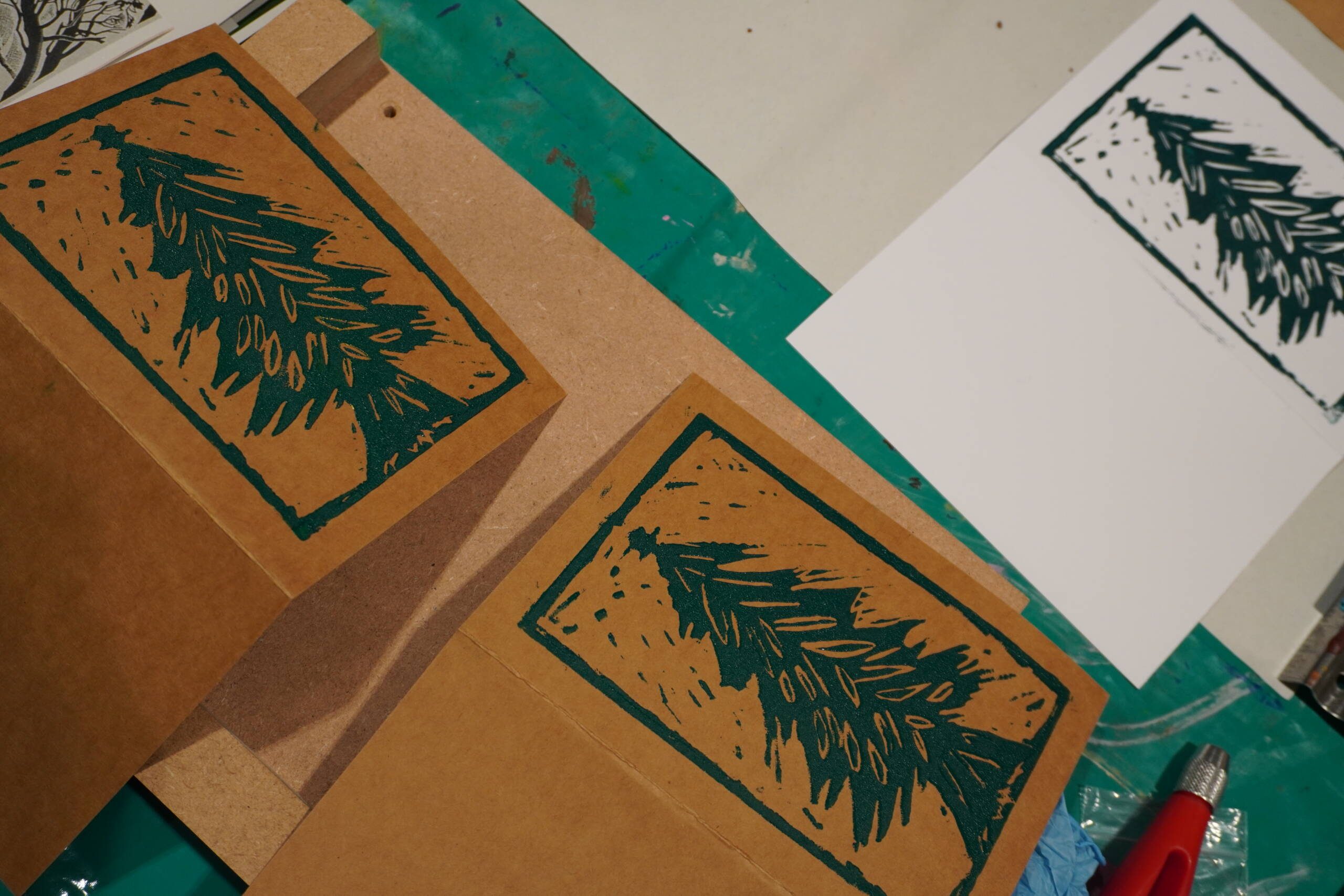 Photograph of two printed Christmas cards with Christmas trees printed in green with a green border.