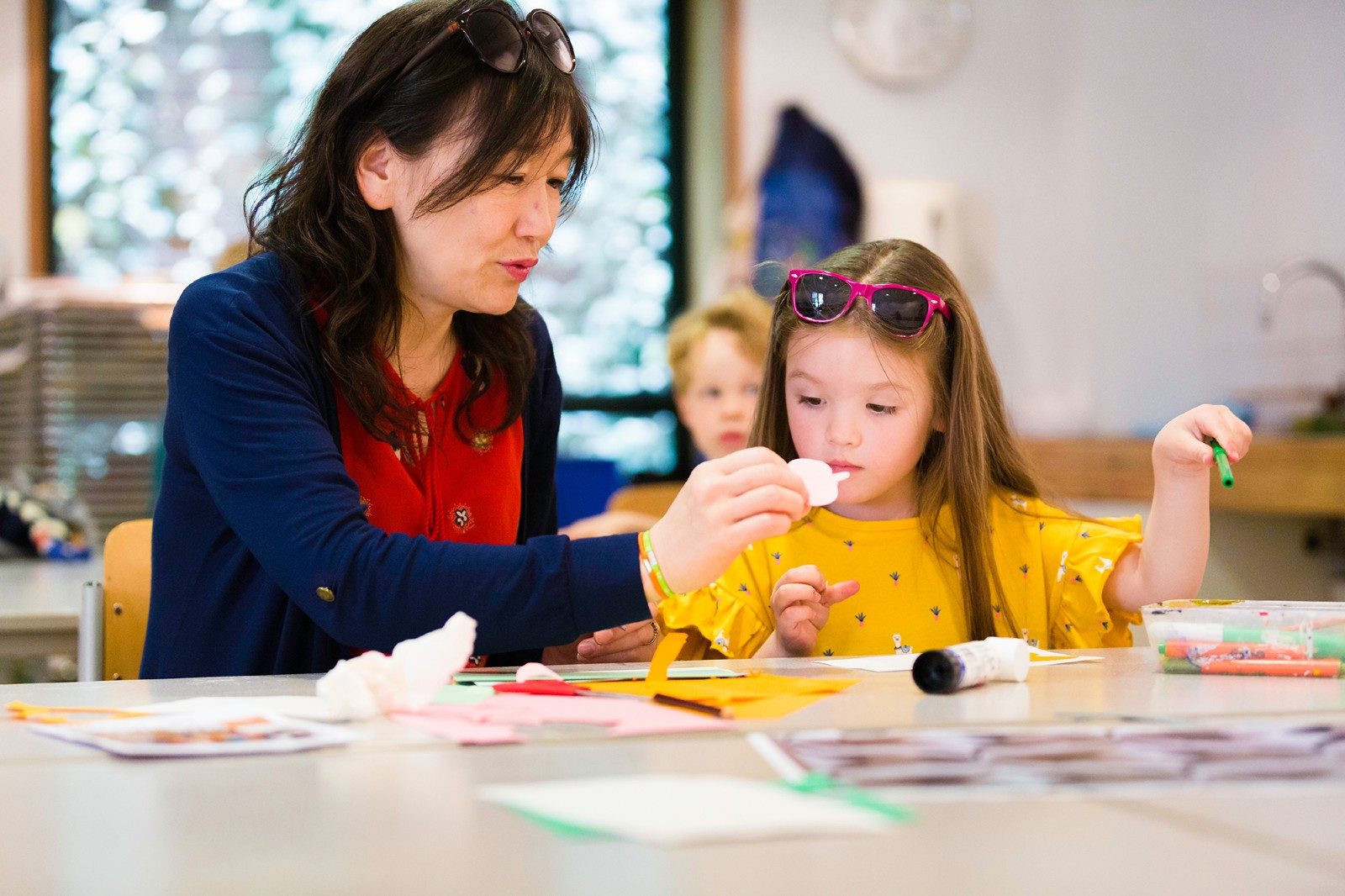 A woman and a young girl sit together at a table creating a collage