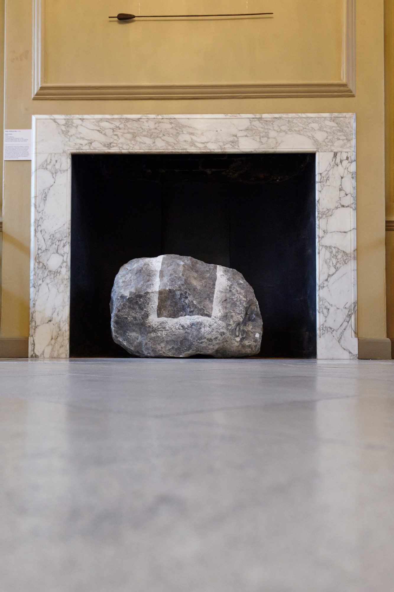 A large chalk stone incised with a square outline sitting in a period fireplace.
